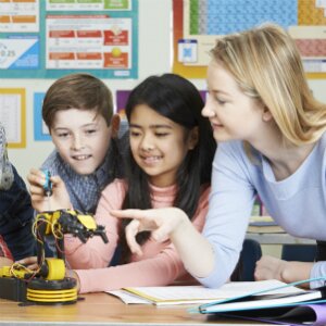 A teacher helps students build a robot. 